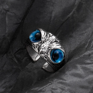 Macro detail of antique silver owl ring featuring intricate metalwork and blue gem eyes