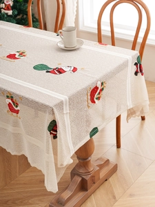 Detailed close-up of Christmas lace tablecloth with embroidered Santa and sleigh patterns