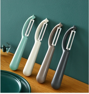Kitchen peeler set in four colors with ergonomic handles on a rustic wood surface
