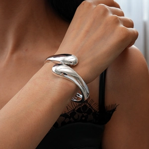 Detailed close-up of glossy silver fluid teardrop cuff bracelet on a model wrist