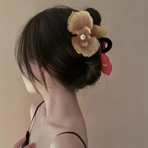 Detail view of a floral hair claw clip with a golden orchid and pearl on a woman's hair
