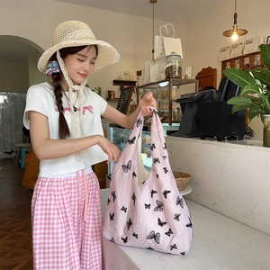 Lifestyle view of large pink tote bag with black butterfly prints and spacious shoulder strap