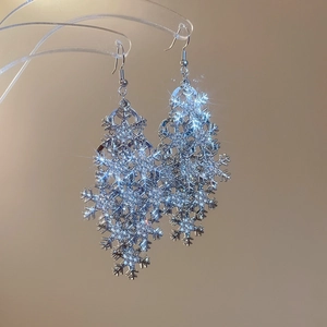 Macro shot of silver snowflake tassel earrings with sparkling rhinestones on stand