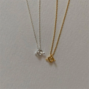 Close-up of gold and silver knot-style heart pendants with thin cable chains