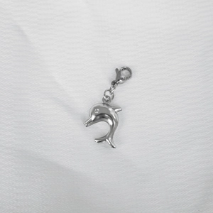 Detailed close-up of a silver dolphin pendant with lobster clasp on white fabric