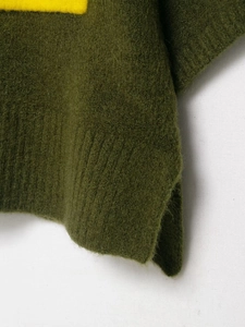Détail d'un pull en maille verte avec texture pelucheuse, accent jaune et bord côtelé