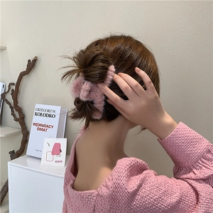 Elegant pink plush hair claw clip worn on a bun for a soft and voluminous hairstyle