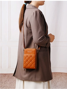 Detail view of tan quilted crossbody phone bag with multi-layer zippers and adjustable strap
