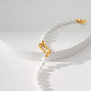 Elegant pearl bracelet with gold rectangular link and lobster clasp on white platform