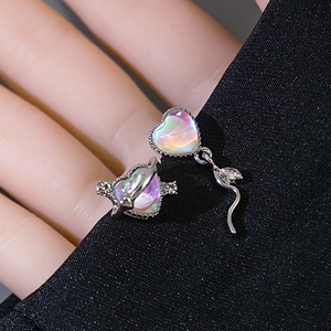 Macro view of heart-shaped silver earrings with iridescent opal stones and rhinestones