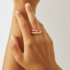 Detail of pink enamel zircon ring and golden twisted band on model's hand