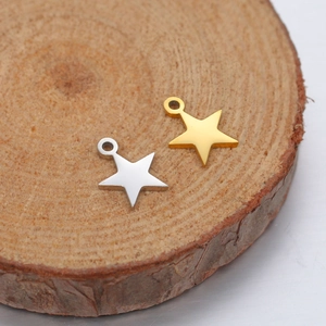 Macro shot of gold and silver star pendants on a rustic wooden base for DIY jewelry