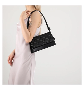 Close-up of black quilted crossbody bag with diamond patterns and knot strap detail