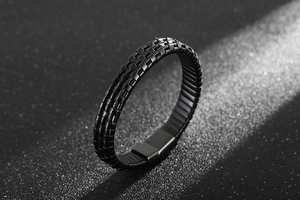Macro shot of black braided leather texture and matte steel magnetic clasp on men's bracelet