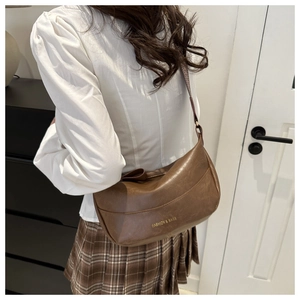 Dettaglio borsa dumpling in pelle PU marrone con scritta dorata FASHION & BAGS lucida