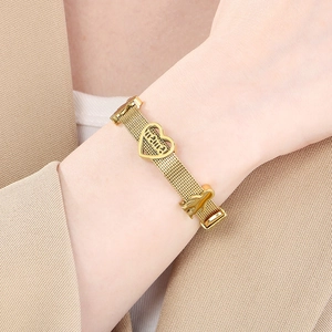 Detail of gold mesh bracelet with heart-shaped MAMA charm and abstract figure pendant