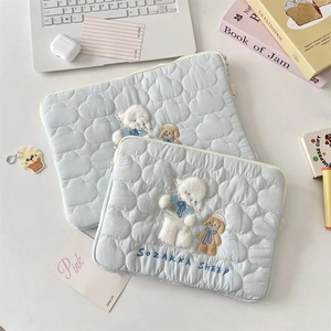 Detalle de fundas acolchadas azul claro para portátil con bordado de oveja y perrito