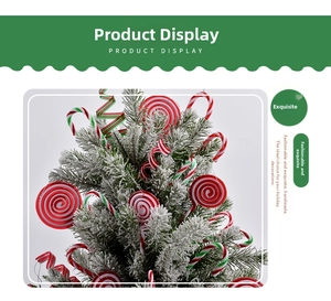Detail of red and white striped candy cane ornaments on a snowy Christmas tree branch