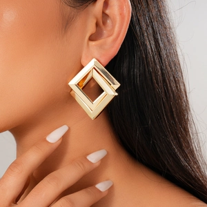 Close-up of golden geometric double-layered hollow diamond earrings on model