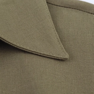 Dettaglio macro del colletto a punta con cuciture su abito midi in lino verde