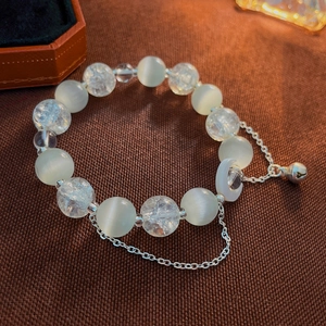 Detailed macro shot of vintage opal beaded bracelet with a delicate silver bell charm