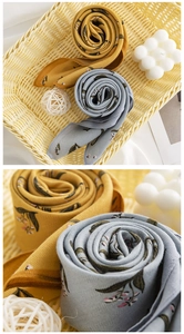 Detail of silk-like floral scarves in yellow and blue-grey showing smooth satin texture