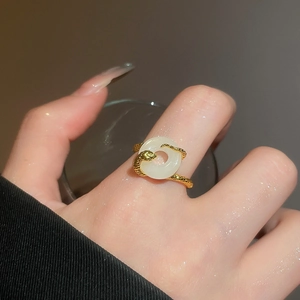 Macro shot of gold plated snake ring with white stone detail on woman finger