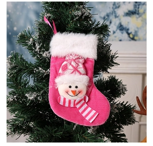 Détail d'une chaussette de Noël rose avec bonhomme de neige 3D sur une branche décorée