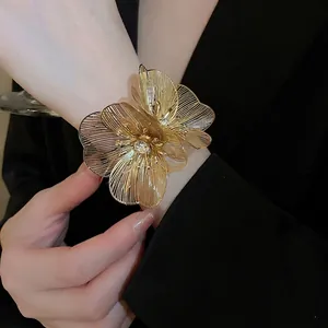 Elegant gold flower cuff bracelet with sparkling crystal centers on black suit background