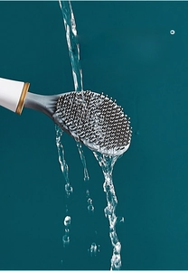 Détail du rinçage à l'eau des poils gris d'une brosse de toilette en silicone blanc