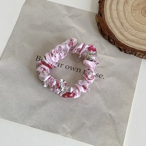 Close-up of pink floral fabric scrunchie with red flowers on a minimalist background
