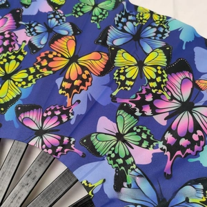 Close-up of colorful butterfly prints on dark blue fabric of a bamboo folding fan