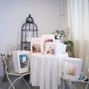 Detail of white and pink gift bags with large PVC windows showing plush bears and flowers