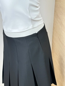 Detail view of the side hidden zipper and pleated design on black mid-length skirt