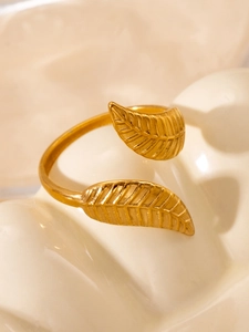 Macro detail of golden open leaf ring showing intricate texture on ceramic stand