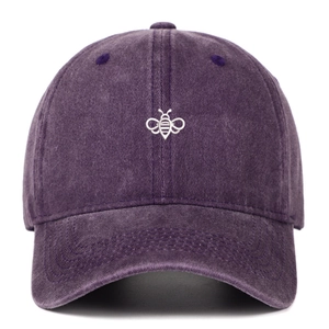 Close-up of embroidered bee on washed dark purple cotton baseball cap with vintage texture