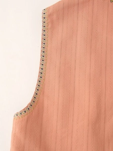 Detailed close-up of orange-pink fabric texture with ethnic beaded embroidery on armhole
