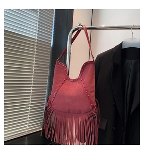 Detail of red suede tassel bag featuring vintage sun embossing and metallic stud accents
