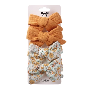 Set of four fabric hair bows with floral and solid patterns on a display card