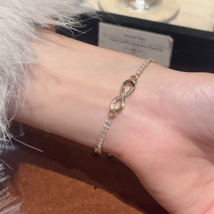 Close-up of golden infinity charm bracelet with pavé cubic zirconia on model's wrist