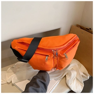 Detail of orange crossbody bag with multiple zippers and wide black strap