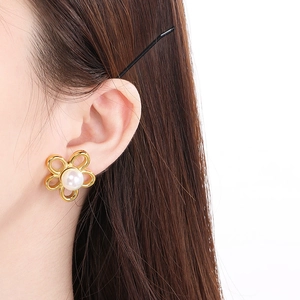 Gros plan d'un modèle portant la boucle d'oreille fleur évidée en or 18K et perle