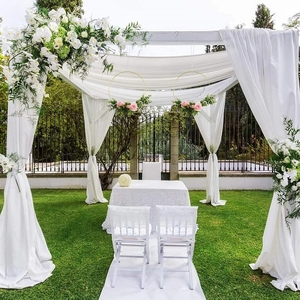Wedding arch iron ring decorated with white drapery and pink floral arrangements