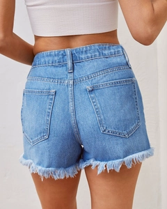 Détail du short en jean bleu clair à taille haute avec ourlets effilochés et poches arrière