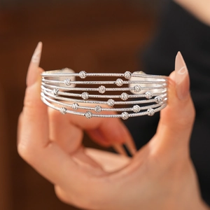 Détail d'un bracelet ouvert multicouche argenté orné de perles en métal texturé
