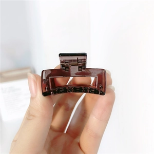 Macro shot of small square amber hair claw clip held in hand showing compact size