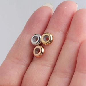 Close-up of 8mm stainless steel stopper beads in silver, gold, and rose gold on a finger
