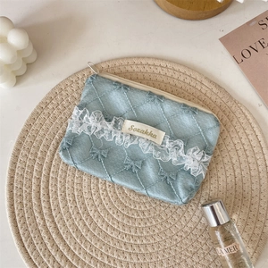 Close-up of blue quilted coin purse with white lace trim and secure top zipper closure