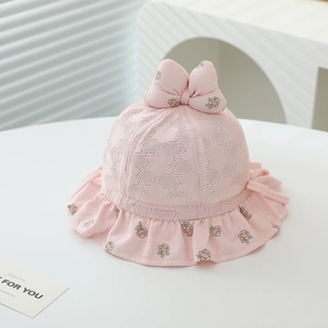 Détail d'un chapeau de soleil rose pour bébé avec motifs floraux, dentelle et grand noeud