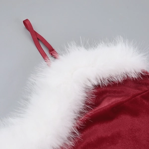 Detail van rode fluwelen kerstjurk met witte nepbontrand en delicate schouderbandjes